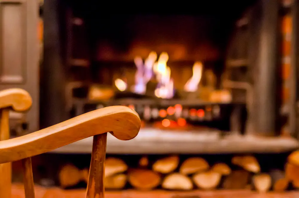 Une chaise en bois devant une cheminée